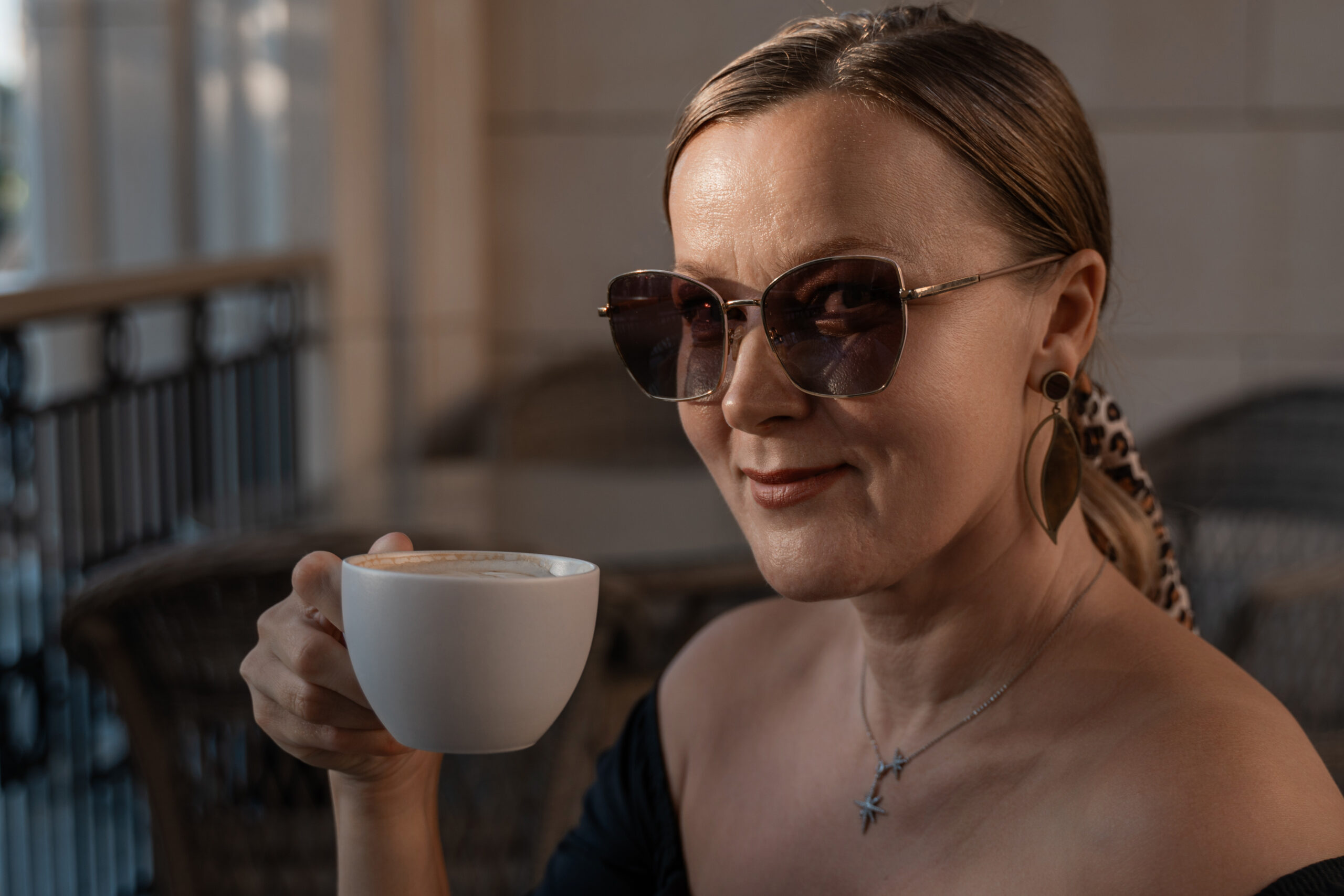 woman in sunglasses holds a cup of coffee