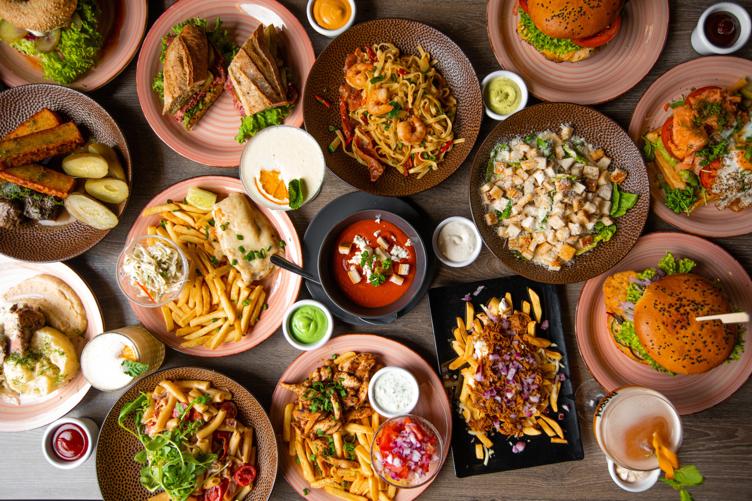 multiple dishes of food on a table, along with sauces and drinks