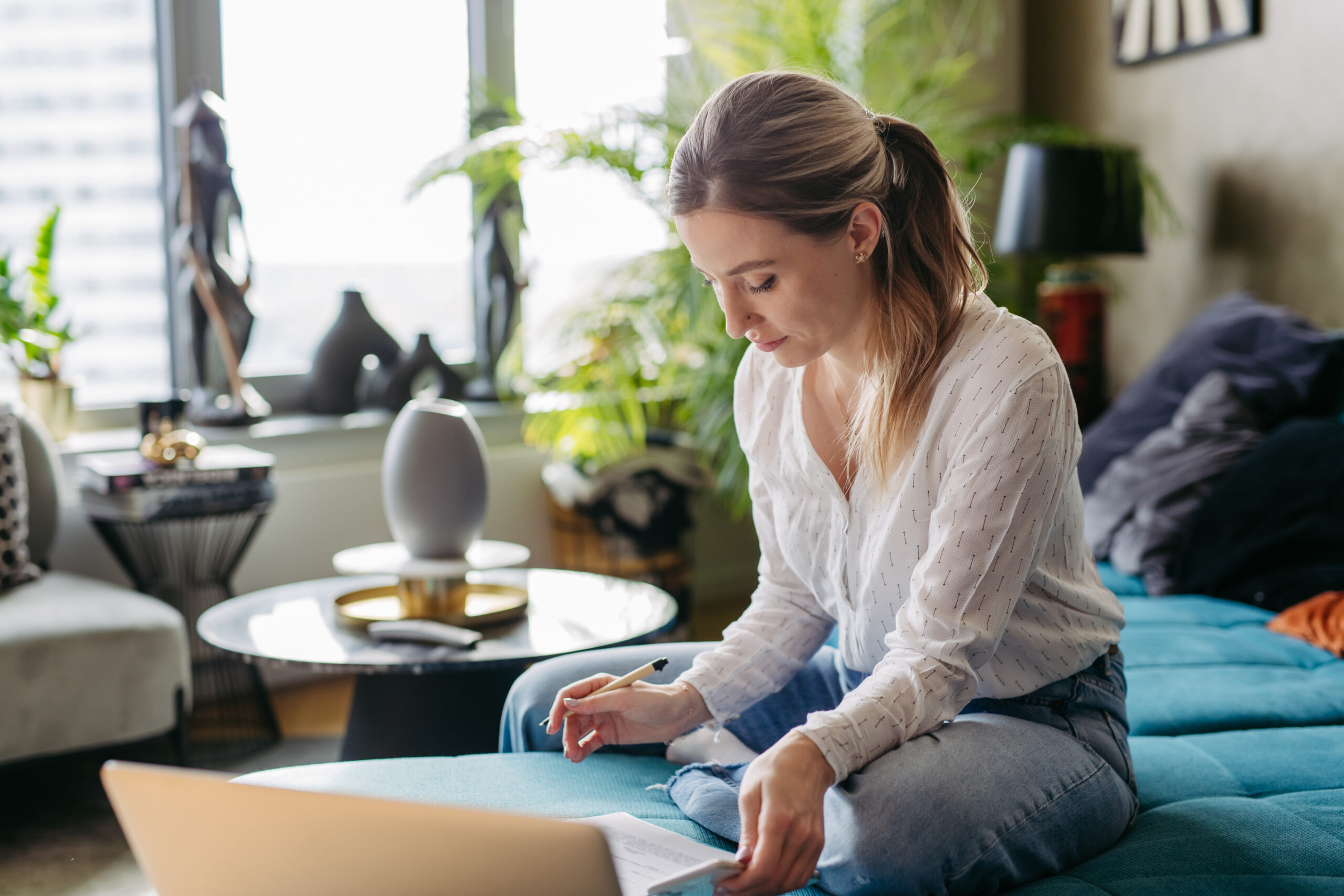 woman sitting in living room with papers and a laptop