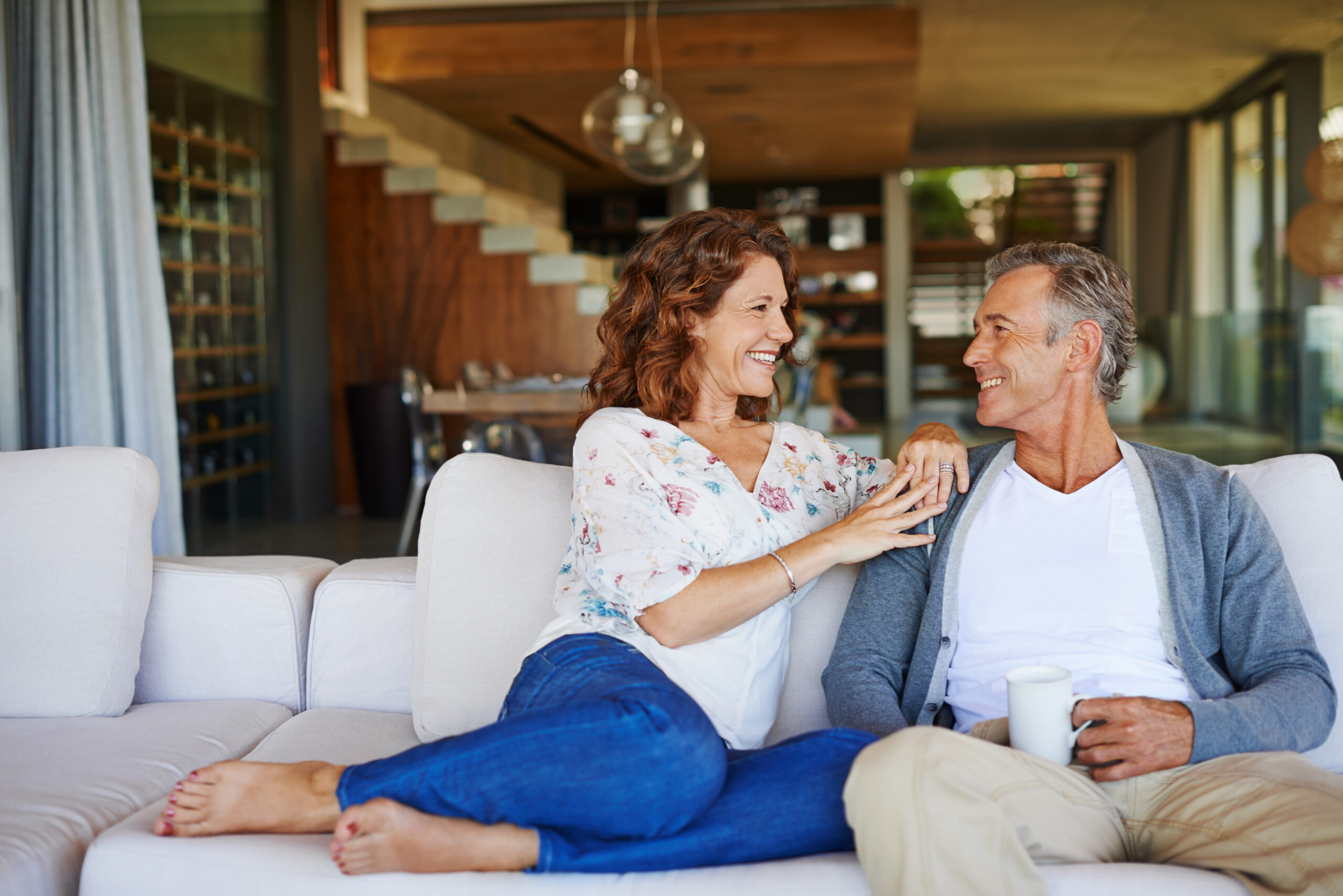 A happy mature couple enjoying a cup of coffee together on the sofa at home.