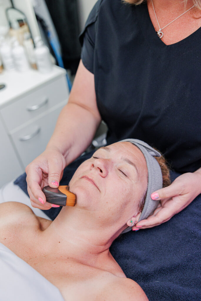 Esthetician lymphatic drainage massage on woman's face with brush