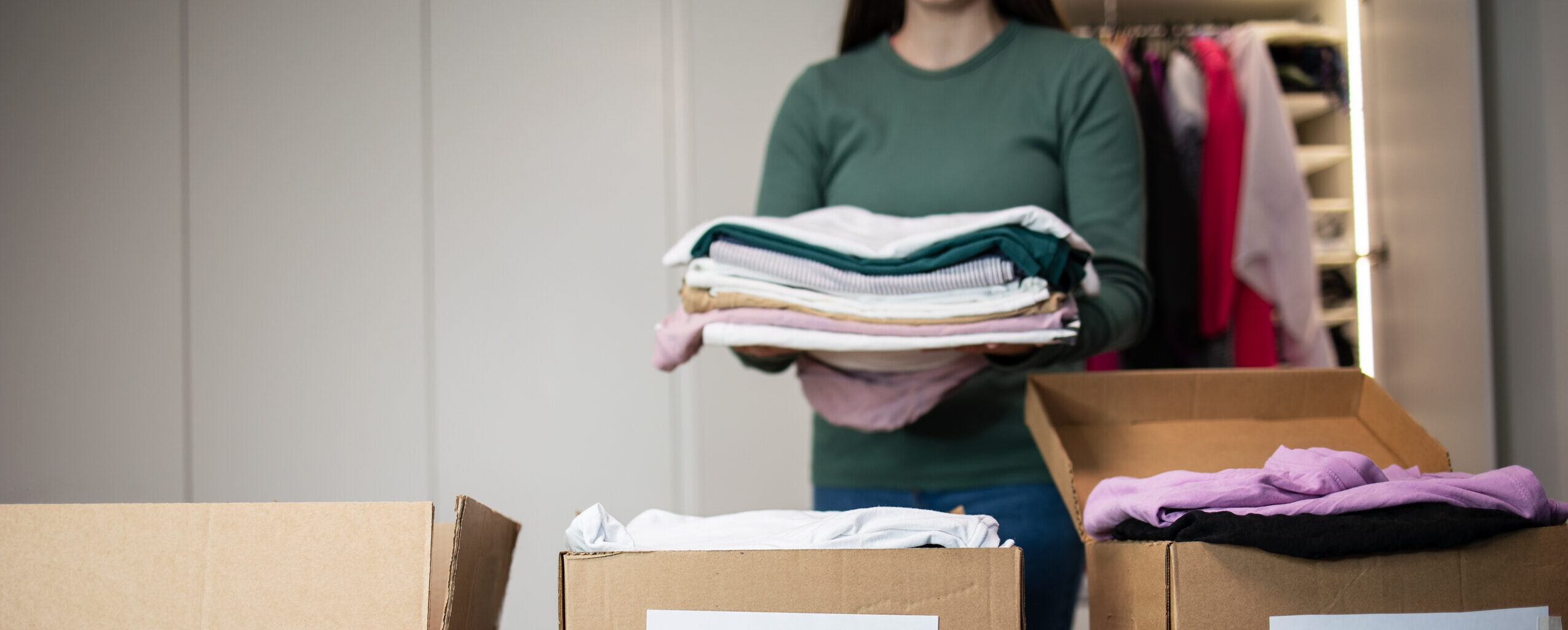 A woman packs clothes in a box for donating clothes