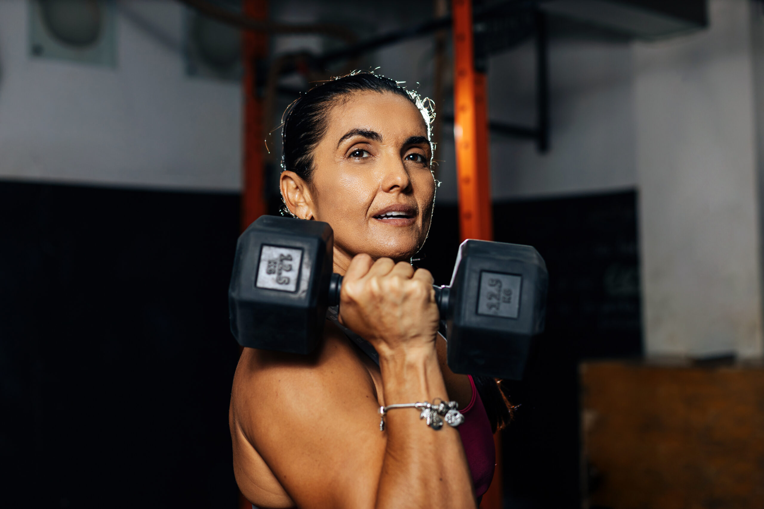 Fitness determined mature woman working out at the gym. Concetrate middle aged lady doing daily exercises.
