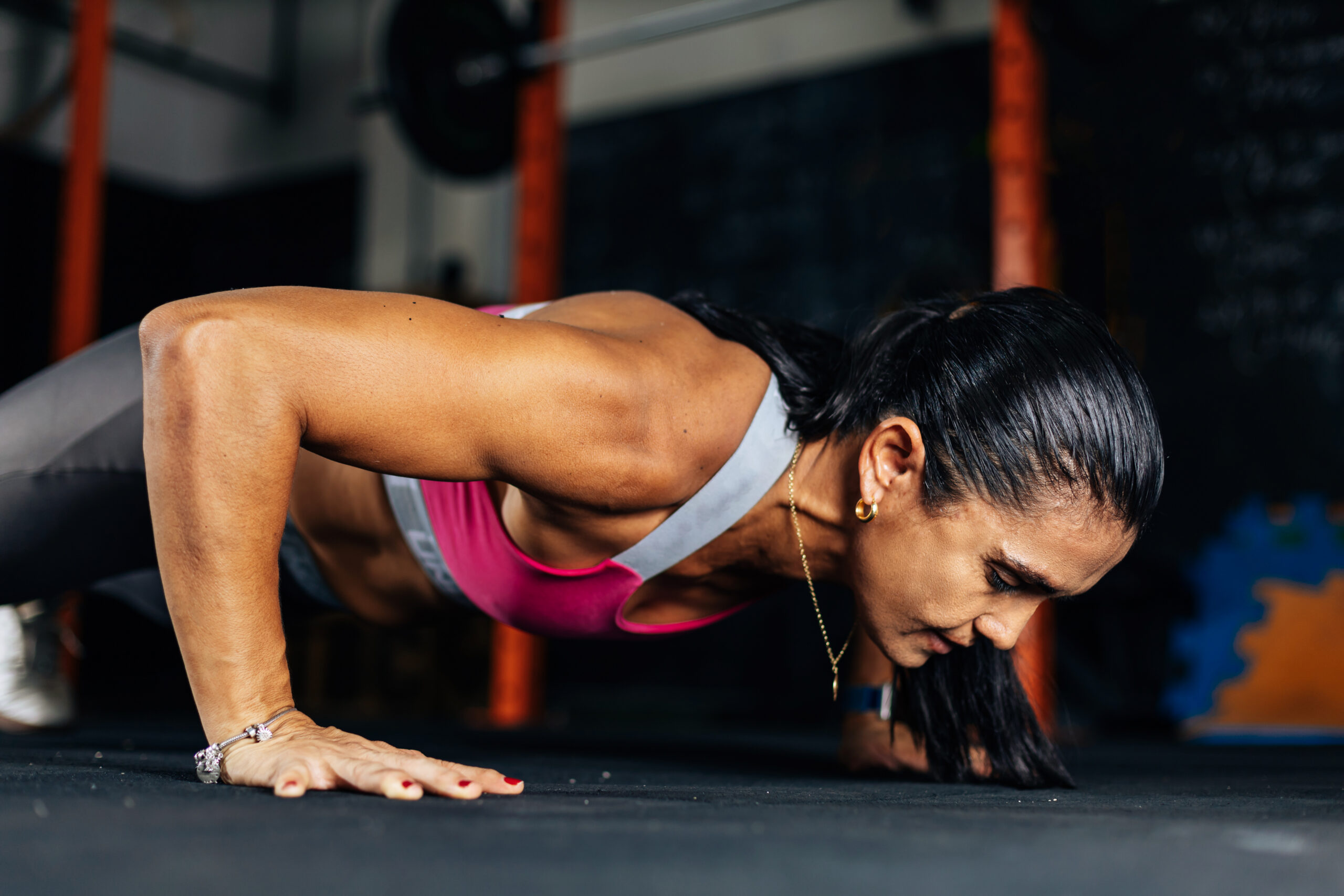 Fitness determined mature woman working out at the gym. Concetrate middle aged lady doing daily exercises.