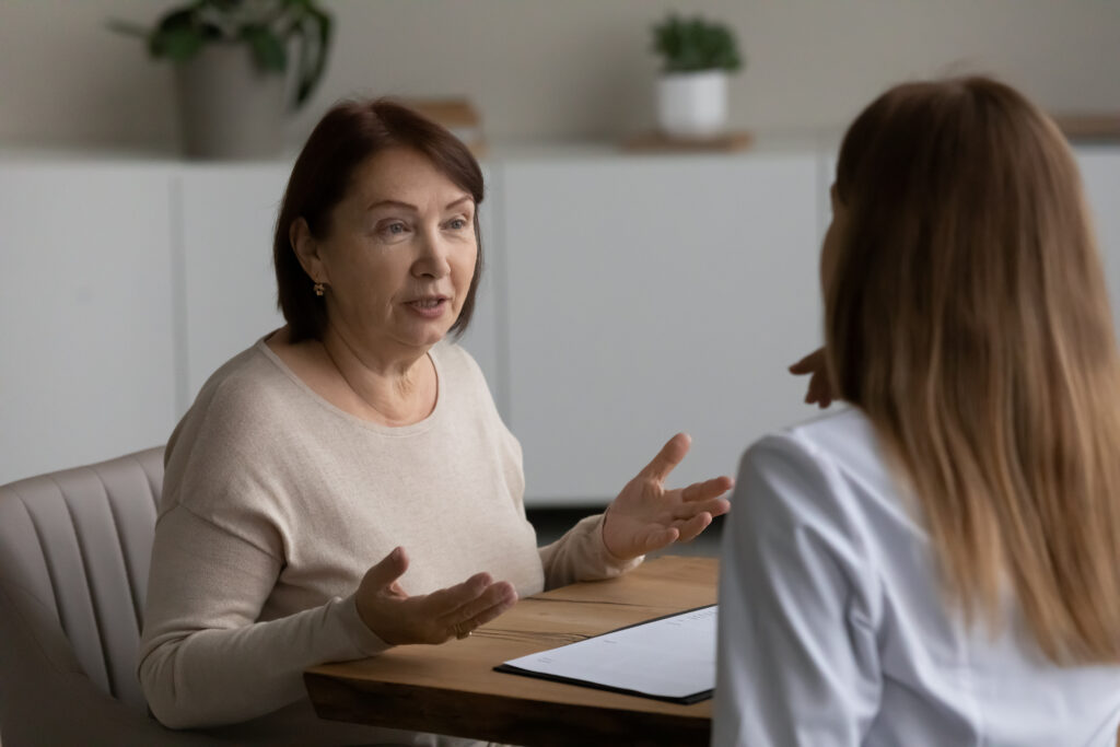 Happy older woman consulting with young doctor.