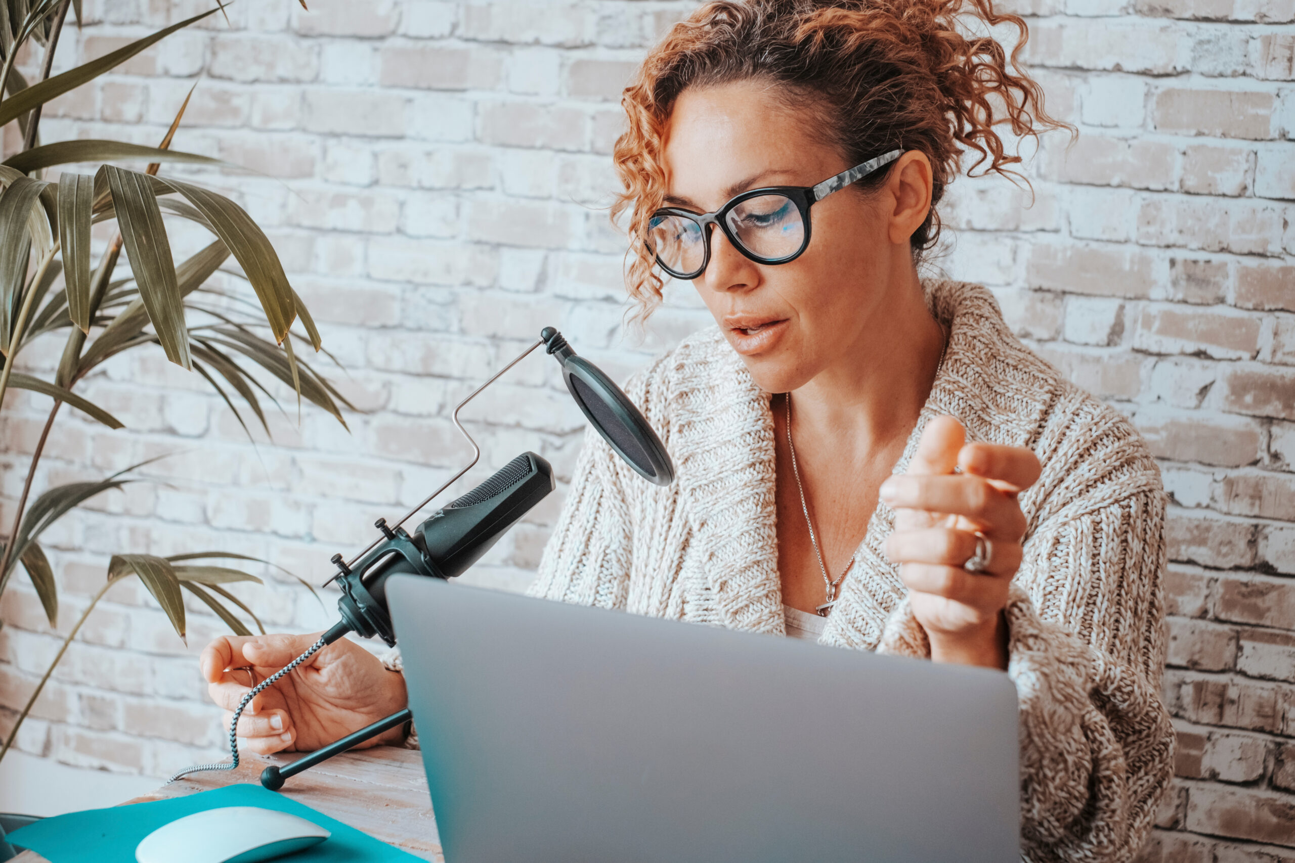 Online woman content creator do podcast speaking on microphone and recording with laptop computer. Concept of modern work job digital business opportunity for technology female people